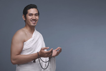 Canvas Print - Young asian muslim man in ihram holding prayer beads