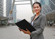 © zilvergolf - Beautiful business woman open cover sheet in her hands outdoors.