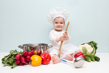 Wall Mural - Baby wearing a chef hat with vegetables and pan. .