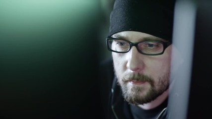 Wall Mural - closeup shot of bearded hacker in eyeglasses looking at computer monitor at night