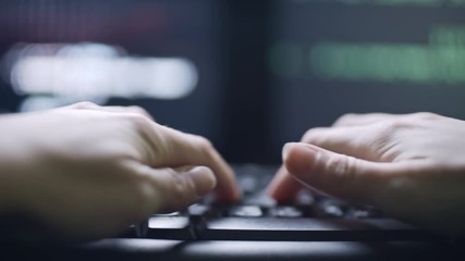 Wall Mural - tracking shot of hands of female hacker typing on computer keyboard; defocused screen with data in b