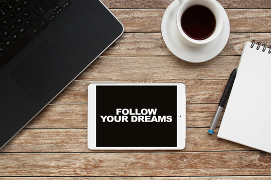 Tablet on desktop with follow your dreams text.