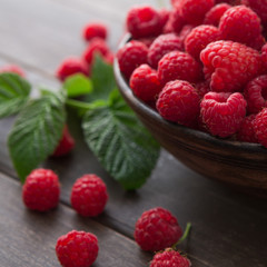 Red fresh raspberries on brown rustic wood background