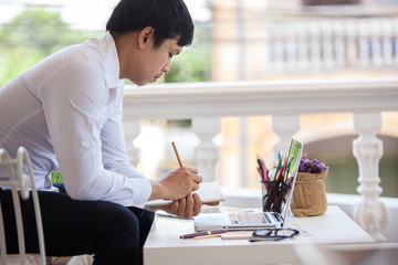 Wall Mural - Man write on notebook with laptop on table