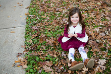 Young Girl Sat In In Autumn Leaves Outside