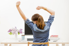 Woman Stretching Her Arms Sitting By The Table At Work Next To Computer