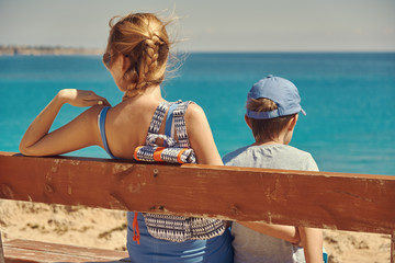 Mom and son spending time sitting on the bench on the coast of the sea. Cape Greko. Cyprus.