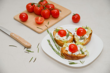 Italian bruschetta with soft cheese, tomatoes, rosemary and fresh salad on the plate. Space for text