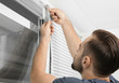 © Africa Studio - Man installing window blinds at home, close up