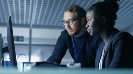 Wall Mural - black female and white male discuss work shown on a computer screen. they work in a bright and moder