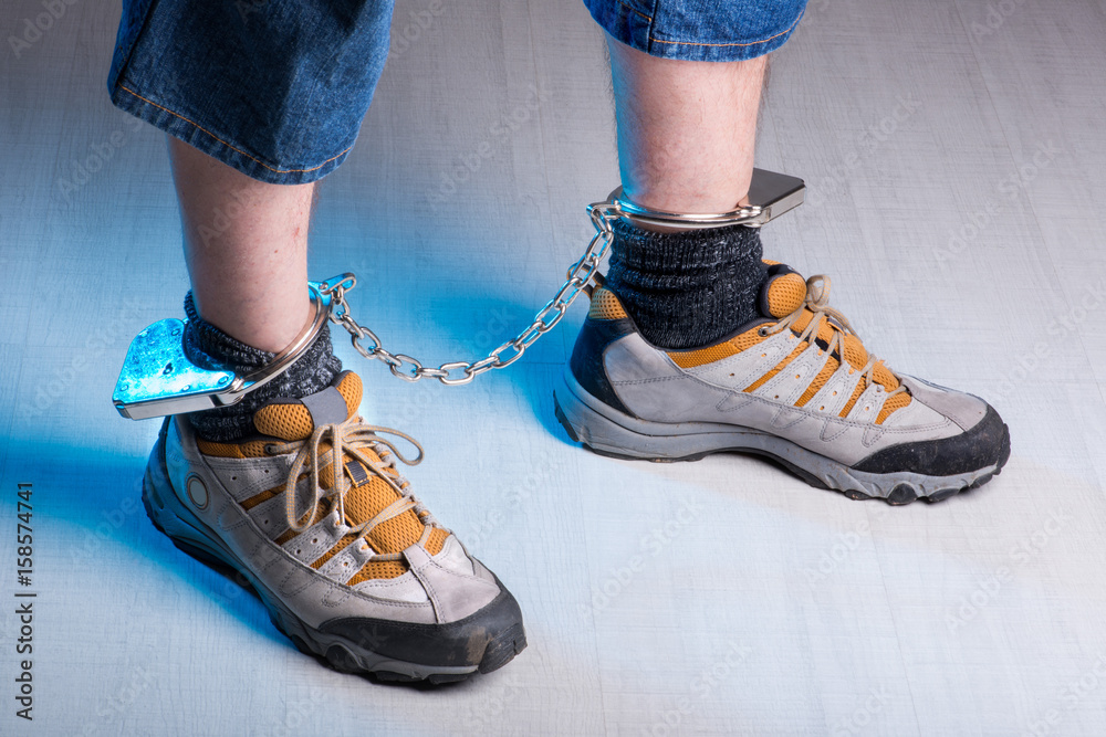 Fußfessel an männlichen Füßen seitlich gehend blau angestrahlt