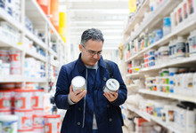 Man Choosing Paint On The Shelves Of A Hardware Store