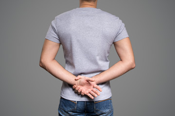 Wall Mural - Gray t-shirt on a young man template. Back view. Gray background.