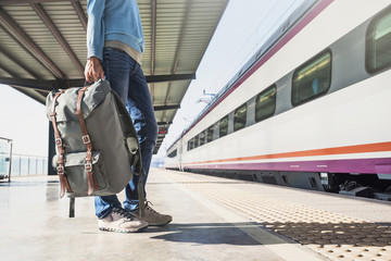 Wall Mural - Young woman traveler waiting for a train on a railroad station, travel and active lifestyle concept