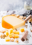 Fototapeta  - Delicious dutch gouda cheese with cheese blocks, crackers, walnuts and special knife on oud wooden table. Copy space.