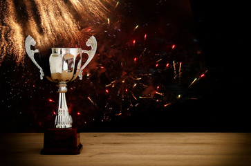 Wall Mural - low key image of trophy over wooden table and dark background