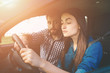 Driving test. Young serious woman driving car feeling inexperienced, looking nervous at the road traffic for information to make appropriate decisions. Man is an instructor, controlling and checking
