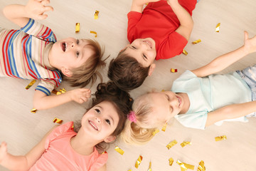 Canvas Print - Cute little children with confetti lying on floor at home