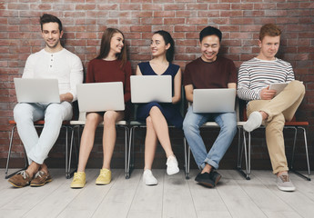 Poster - Young people with gadgets sitting on chairs