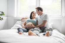 Young Parents In Bed Expecting A Little Baby, Romantic Moments For Pregnant Couple