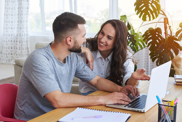 Poster - Good-looking couple smiling to each other while surfing in laptop