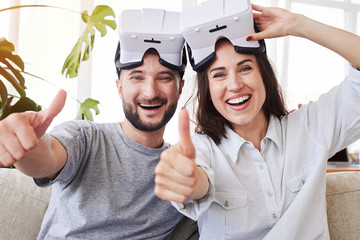 Wall Mural - Smiling pair in VR goggles showing thumbs up