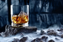 Glass Of Whiskey And Ice.Creative Photo Glass Of Whiskey On Stone With Fog And Cold Background.Copy Space.Advertising Shot