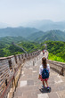 Woman backpacker student walking down the stairs overlooking the landscape of the Great Wall of china at famous Badaling tourist destination during travel vacation in Beijing. Asia summer holidays.