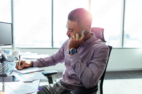 Fotografía Businessman talking over mobile phone sitting at his office desk