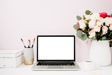 Home Office Desk With Blank Screen Laptop, Beautiful Roses And Eucalyptus Bouquet, White Vintage Casket In Front Of Pale Pastel Pink Background. Blog, Website Or Social Media Concept .