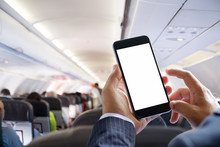 Airplane Passenger Using Smart Phone On Plane. Businessman Touching Blank Screen Mobile Phone At Airplane. For Graphics Display Montage.