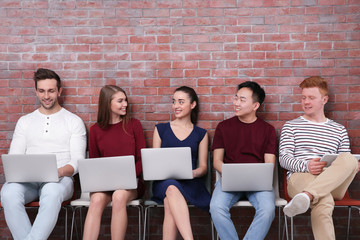 Poster - Young people with gadgets sitting on chairs