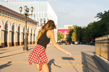 summer holidays, extreme sport and people concept - happy girl riding skateboard on city street