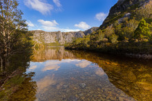 Clear Water At The Rocky Bank Of Crater Lake Surrounded By Mountains At Cradle Mountain, Tasmania, Australia.