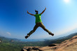 © lzf - successful woman jumping on rocky mountain peak