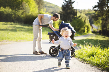 Wall Mural - Father with little son and baby daughter in stroller. Sunny park.