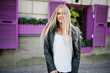 © AS Photo Family - Stylish blonde woman wear at jeans and jacket posed at street against purple window. Fashion urban model portrait.