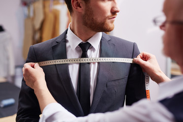 mid section portrait of tailor fitting bespoke suit to model