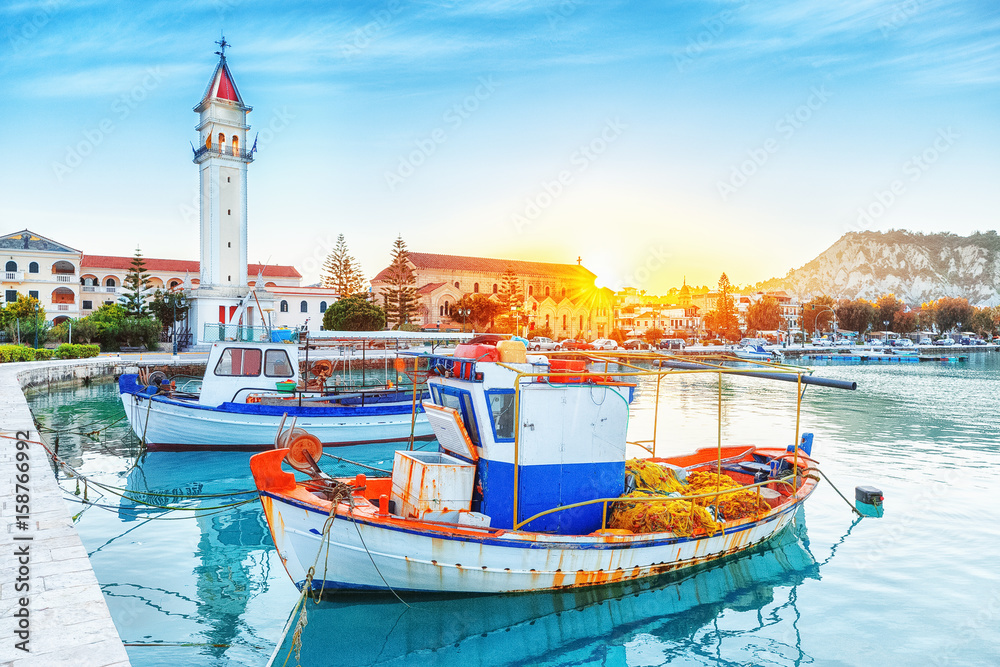 Obraz na płótnie Zante - Zakinthos island, old port with moored boats and church tower landmark. Majestic sunset scenery, sun glowing visible. w salonie