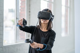 Fototapeta Sypialnia - An asian woman wearing a virtual reality headset.