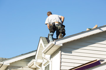 Worker installing new roof on home