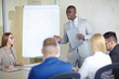 © pressmaster - Concentrated Afro-American manager with clipboard in hands presenting his ideas to colleagues during meeting in modern board room