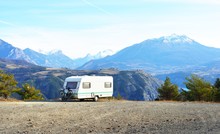 Caravan With A Bike Parked On A Mountaintop With A View On The French Alps Near Lake Lac De Serre-Poncon On A Bright Sunny Day
