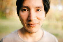 Close Up Portrait Of Native American Peruvian Indian Man With Black Hair, Dark Eyes Looking At Camera With Deep Reflective And Stare Eyes. Nature, Park, Outdoor. Abstract Background.