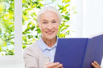 Wall Mural - happy smiling senior woman reading book at home