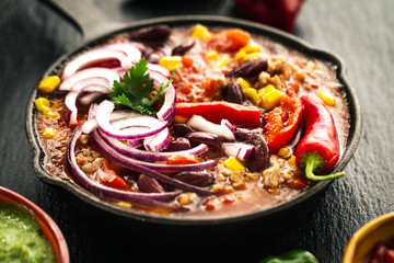 Poster - Tasty appetizing mexican food stew in iron pan on dark background closeup.