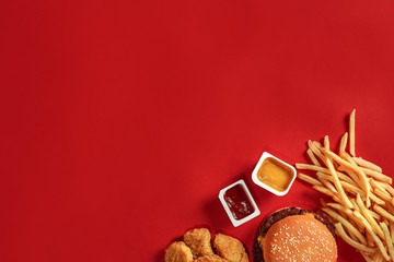 Burger and Chips. Hamburger and french fries in red paper box. Fast food on red background.