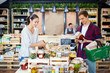 © pressmaster - Young couple reading labels on jars while doing shopping in local store with farm products