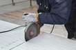 © sima - Worker using angle grinder to cut roof or wall panel at construction site