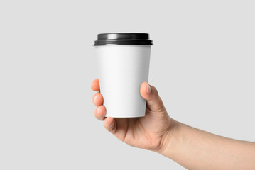 Wall Mural - Mockup of male hand holding a Coffee paper cup isolated on light grey background. 